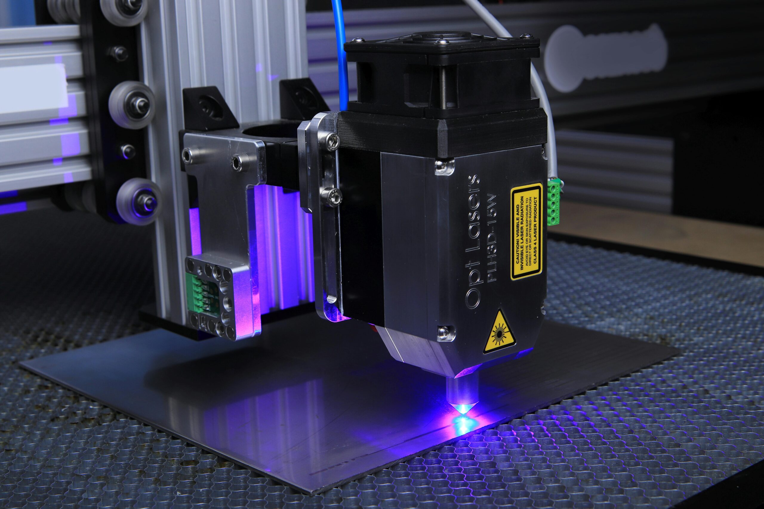Close-up of a laser engraving machine operating on a metal surface with blue laser light.